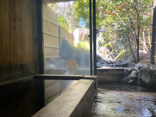 a room with a window with a view of a waterfall at Ryoso Yufuin Yamadaya in Yufuin