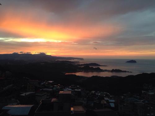 a sunset over a city with the ocean in the background at 隱山居 海景包棟2-10人 in Jiufen