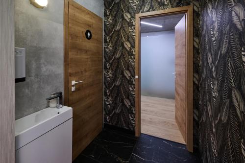 a bathroom with a door leading to a shower at GRANDIS Premium Apartments in Gödöllő