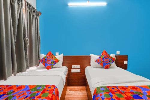 two beds with colorful pillows in a room at Hotel RLV Green Palace - Nr Kengeri Satellite Town in Bengaluru