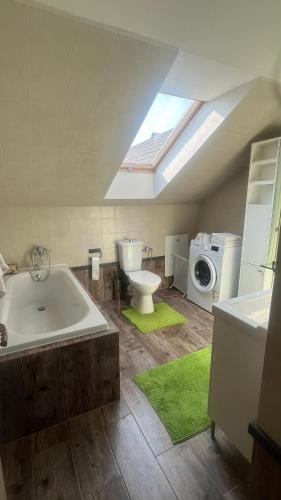 a bathroom with a tub and a toilet and a washing machine at Samostatný byt v rodinnom dome in Revúca