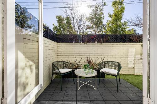 a patio with a table and chairs and a brick wall at Windsor Apartments by Urban Rest in Melbourne
