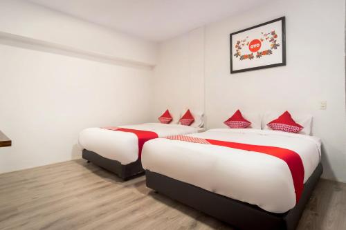 two beds in a room with white walls and red pillows at Super OYO 835 Metropolitan Home Stay in Medan