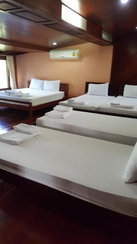 a group of three beds in a room at Ruean Mai Chai Khlong in Amphawa