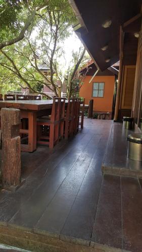 an empty patio with a wooden table and chairs at Ruean Mai Chai Khlong in Amphawa