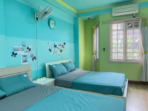 a bedroom with two beds and a clock on the wall at Lava Homestay Hải Phòng in Hai Phong
