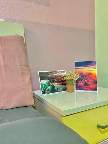 a table with two pictures on it next to a bed at Lava Homestay Hải Phòng in Hai Phong