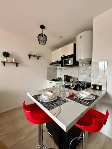 une cuisine avec un comptoir et deux chaises rouges dans l'établissement Jasmin Roanne centre-ville - Parking & Clim, à Roanne