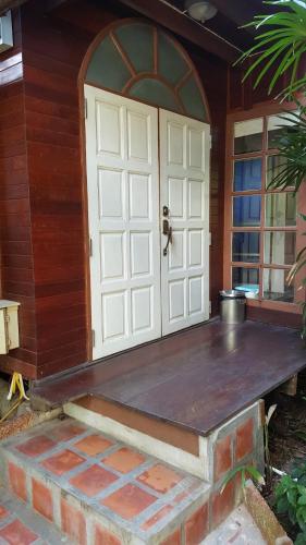 a porch with a white door on a house at Ruean Mai Chai Khlong in Amphawa