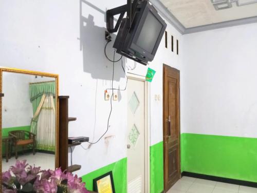 a tv on the wall of a room with a mirror at Puspa Tiara Syar'i Guci Mitra RedDoorz in Tuwel