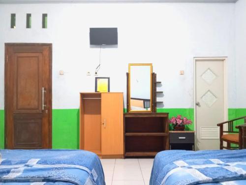 a room with two beds and a mirror at Puspa Tiara Syar'i Guci Mitra RedDoorz in Tuwel