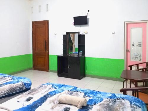 a room with two beds and a table and a mirror at Puspa Tiara Syar'i Guci Mitra RedDoorz in Tuwel