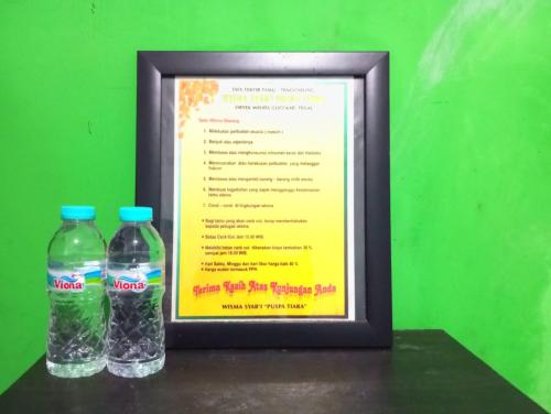 two bottles of water sitting next to a menu at Puspa Tiara Syar'i Guci Mitra RedDoorz in Tuwel