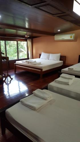 a room with three beds and a window at Ruean Mai Chai Khlong in Amphawa