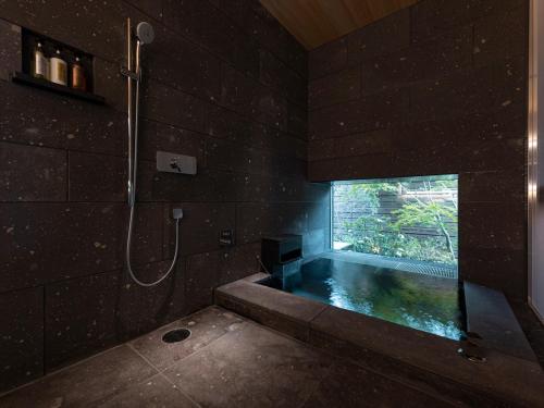 a bathroom with a bath tub with a window at THE BLOSSOM KUMAMOTO in Kumamoto