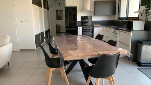 une cuisine avec une table en bois et des chaises noires dans l'établissement Villa Jules Verne, au Crotoy