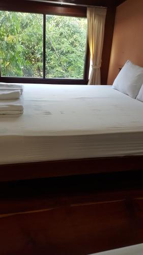 a bedroom with a large bed with a window at Ruean Mai Chai Khlong in Amphawa