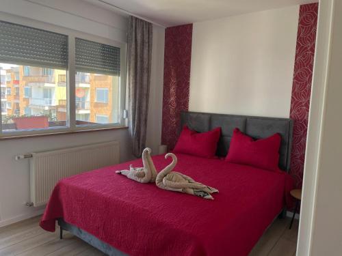 two swans are sitting on a red bed at Apartman Lana in Teslić