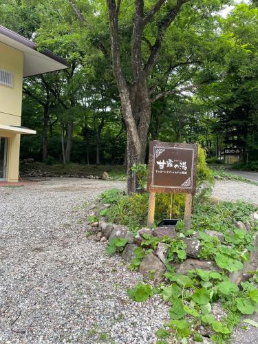 a sign sitting in the gravel next to a tree at ドゥカーレリゾートホテル那須甘露の湯 in Nasu-yumoto