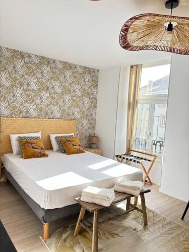 une chambre avec un grand lit et une fenêtre dans l'établissement Mimosa Roanne centre-ville - Parking & Clim, à Roanne