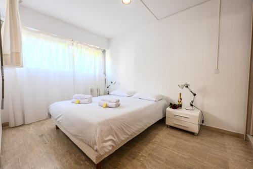 une chambre blanche avec un lit et une fenêtre dans l'établissement Roca Mare 1 bloc B apt 01 - Happy Rentals, à Menton