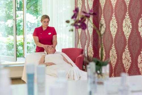 a woman in a room with a woman sitting on a bed talking to a man at Hotel & Spa Der Steirerhof in Bad Waltersdorf