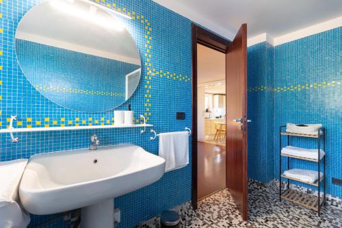 Un baño con azulejos azules, lavabo y espejo. en Al Civico 1, en Conversano