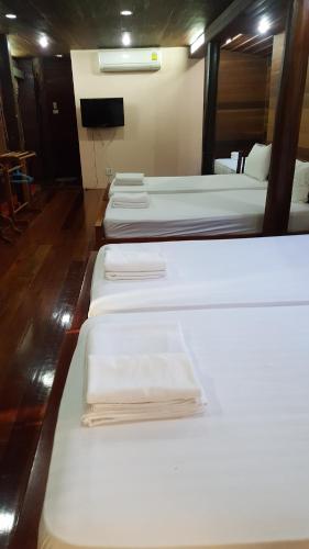a group of four beds in a room at Ruean Mai Chai Khlong in Amphawa