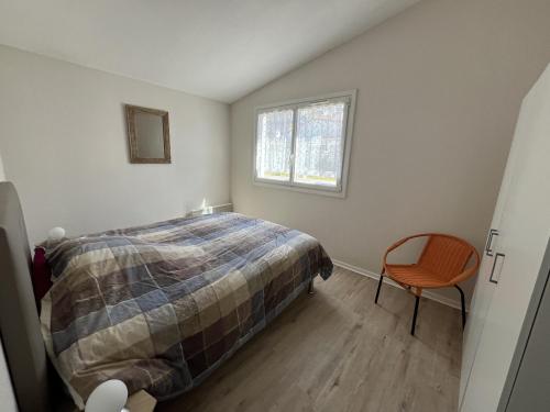 a bedroom with a bed and a chair in it at L'Océanide in Saint-Gilles-Croix-de-Vie