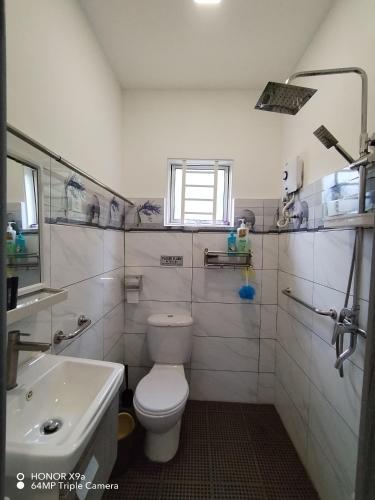 a white bathroom with a toilet and a sink at Z&S Gerik Hillview Homestay in Gerik
