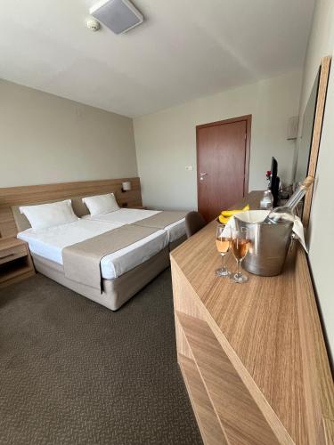 a hotel room with a bed and a table with wine glasses at Relax Coop Hotel in Voneshta Voda