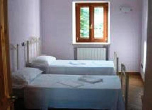 drei Betten in einem Zimmer mit Fenster in der Unterkunft Locanda Dl'Angel in Villar San Costanzo