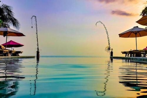 a swimming pool with umbrellas and the ocean at Raveena 1 BR Classic Garden Room Double ZN139 in Mangsit