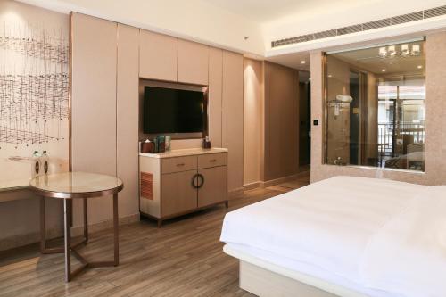a bedroom with a bed and a tv and a table at Wanda Realm Xiamen North Bay in Xiamen