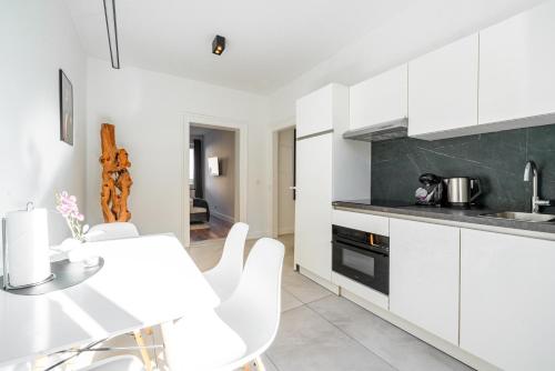 a kitchen with white cabinets and a table and chairs at Nurban Apartments City 2 in Nürnberg