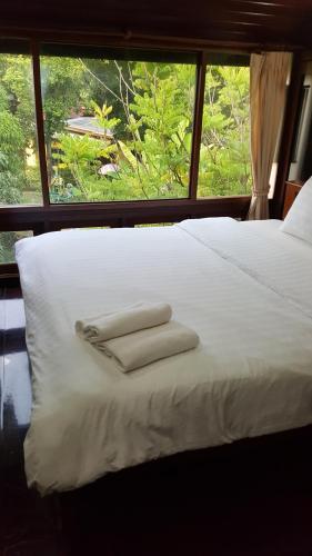 a bed with two towels on it with a window at Ruean Mai Chai Khlong in Amphawa