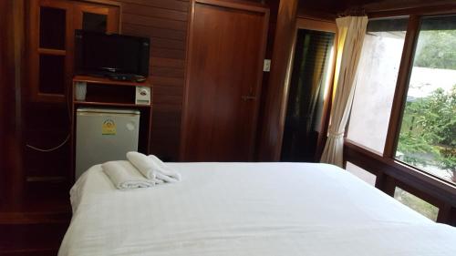 a bedroom with a bed with towels on it at Ruean Mai Chai Khlong in Amphawa