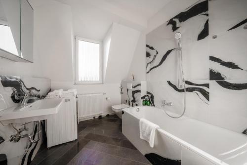 a bathroom with a sink and a tub and a toilet at Nurban Apartments City 2 in Nürnberg