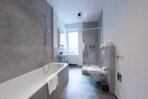 a bathroom with a tub and a toilet and a sink at Nurban Apartments City 2 in Nürnberg