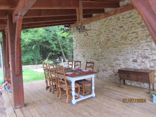 - une table et des chaises sur une terrasse couverte avec un piano dans l'établissement Moulin du XIIème siècle, à Bersac-sur-Rivalier