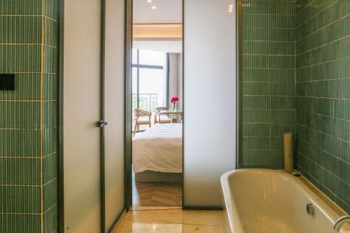 a bathroom with a tub and a bedroom with a bed at Wanda Realm Xiamen North Bay in Xiamen