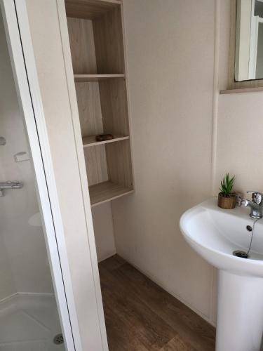a bathroom with a sink and a toilet and a mirror at 20 Cherry Tree Walk Lyons Robin Hood in in Rhyl