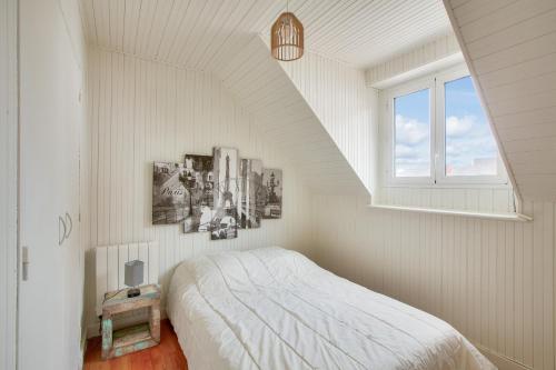 une chambre blanche avec un lit et une fenêtre dans l'établissement A 190m de la plage, hyper centre, maison pour 8, à Pléneuf-Val-André