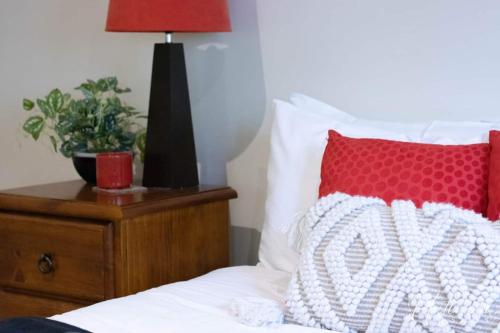 a bed with a red and white pillow on a night stand at Magnolia By Lake in Wendouree