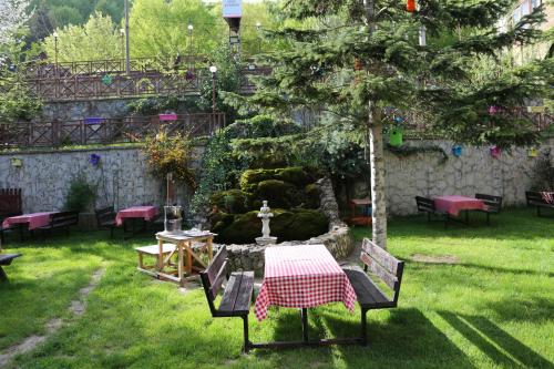 a table and chairs in a garden with a fountain at ABANT DORT MEVSİM KONAĞI HOSTEL in Dereceören
