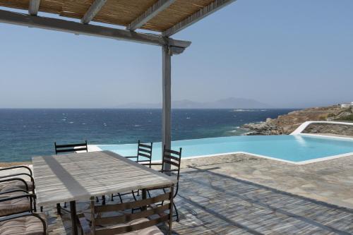 a wooden table and chairs next to a swimming pool at Villa Coventina in Agios Ioannis Mykonos