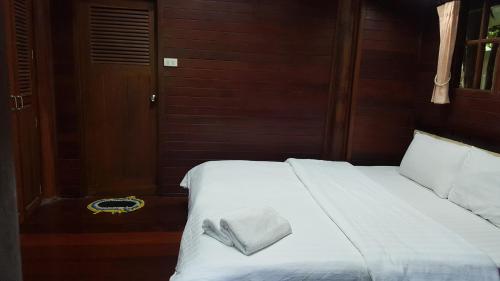 a white bed with a towel on top of it at Ruean Mai Chai Khlong in Amphawa