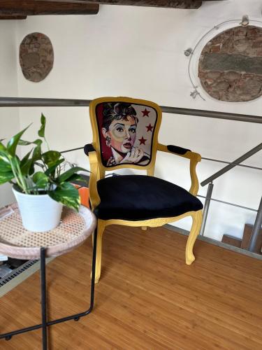 a chair with a painting on it next to a table at La Casetta del Centro Luminoso loft con terrazzo e giardino in Biella
