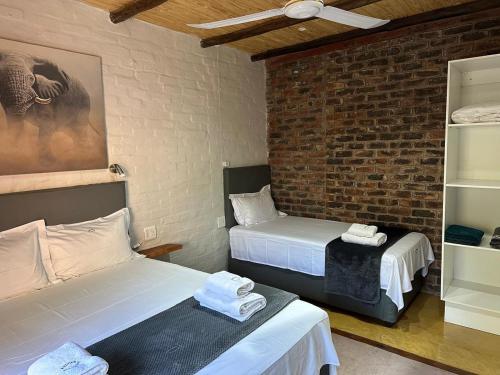 a room with two beds and a brick wall at Kruger Wild Dog Inn in Marloth Park