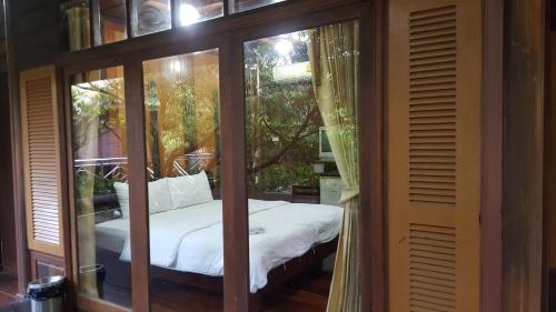 a glass room with a bed inside of it at Ruean Mai Chai Khlong in Amphawa